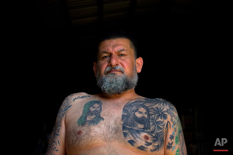 In this Tuesday, May 31, 2016 photo, Ali Hussein Nasreddine, 50, poses for a photo showing his tattoo of Shiite Muslims' first Imam Ali, and his son Imam Hussein, the grandson of the Prophet Muhammed, in the southern suburb of Beirut. (AP Photo/Hassan Ammar)