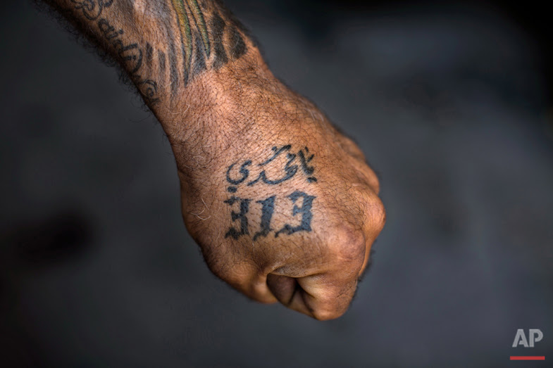 In this Tuesday, May 10, 2016 photo, Ali Hussein Nasreddine, 50, poses for a photo showing off his tattoos with Shiite Muslim religious slogans in the southern suburb of Beirut. The tattoo in Arabic reads, "Oh Mahdi, 313." (AP Photo/Hassan Ammar)