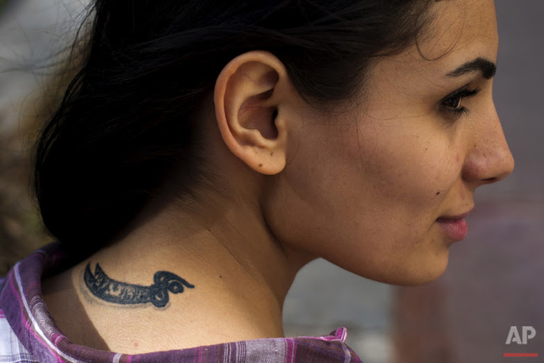 In this Wednesday, May 25, 2016 photo, Farah Najm, 21, an aviation maintenance student, poses for a photo showing her tattoo of the sword of Shiite Muslims' first Imam Ali, in Beirut. (AP Photo/Hassan Ammar)